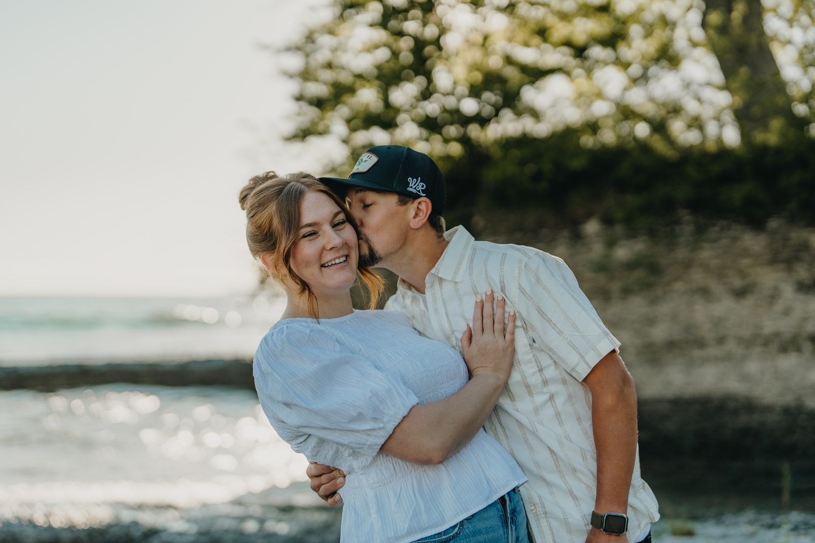 Couple embracing at golden hour during a Point Petre engagement session on the Lake Ontario shoreline in Prince Edward County