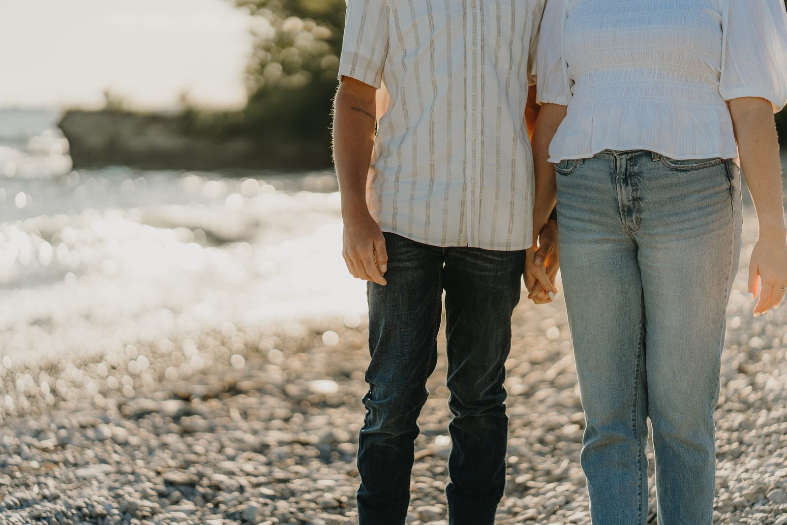 Close-up of an engaged couple holding hands on the shore of Lake Ontario at Point Petre