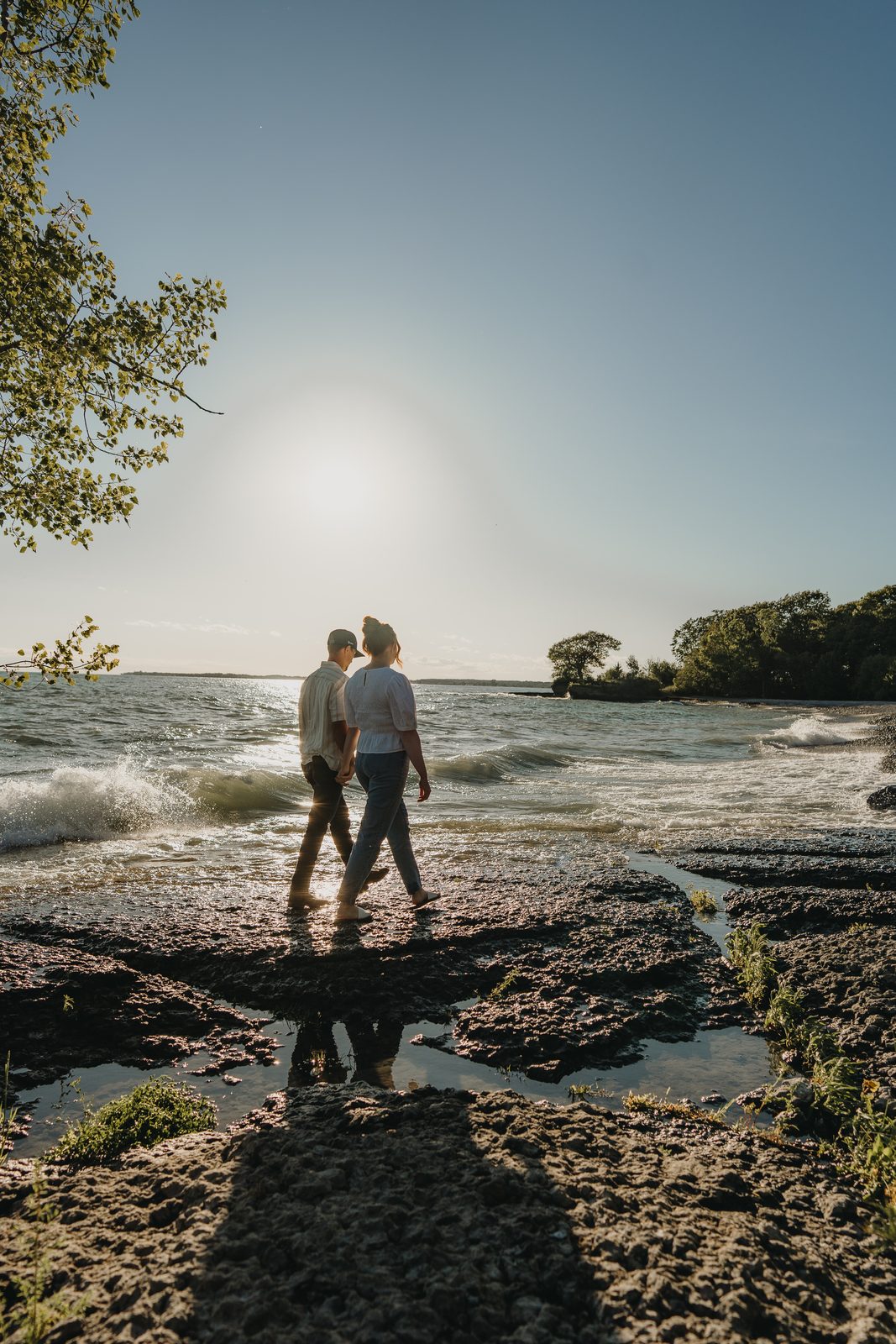 Engaged couple on the Point Petre beach with Lake Ontario behind them