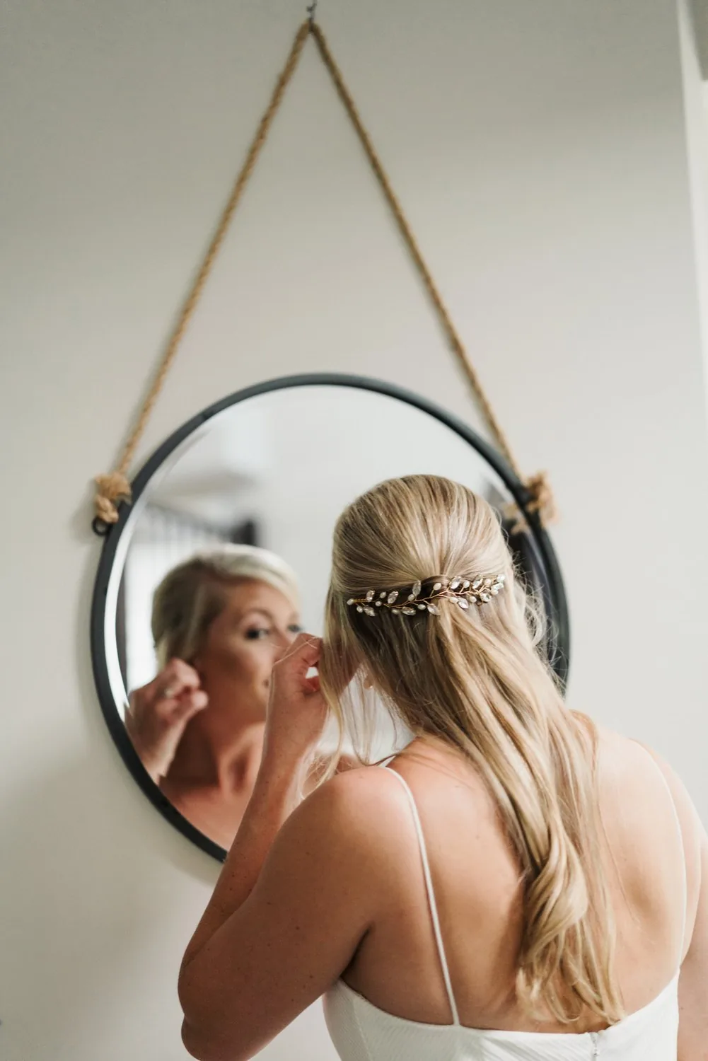 Bride getting ready in front of a round mirror at her family home before her backyard wedding near Kitchener