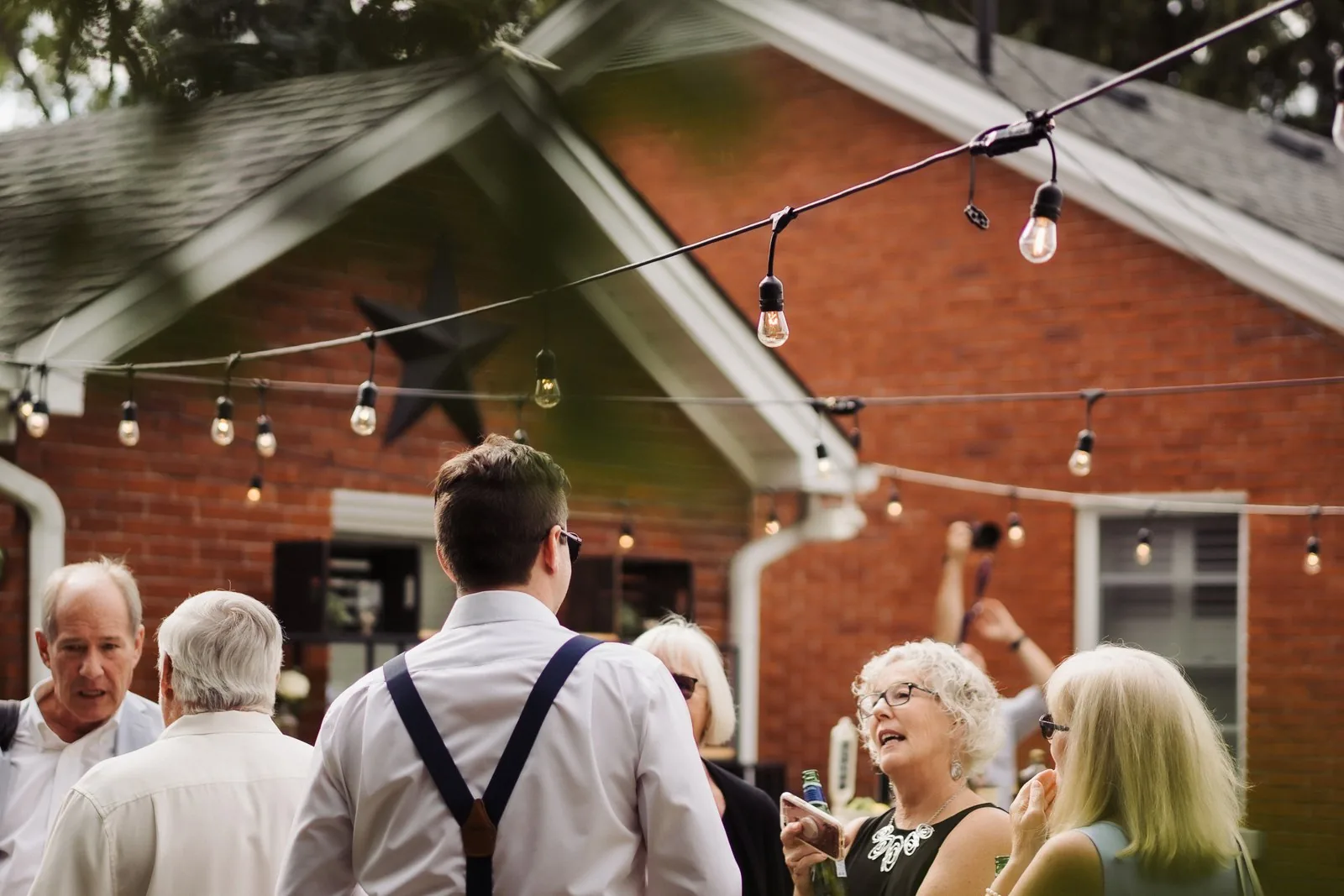 Guests mingling under string lights at an evening backyard wedding reception near Kitchener, Ontario