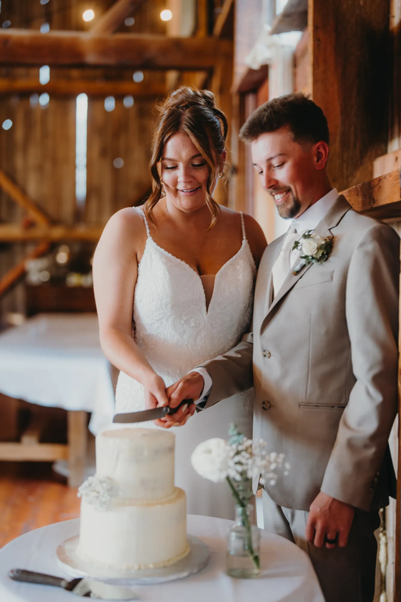 Bride and groom cutting their wedding cake inside the barn
