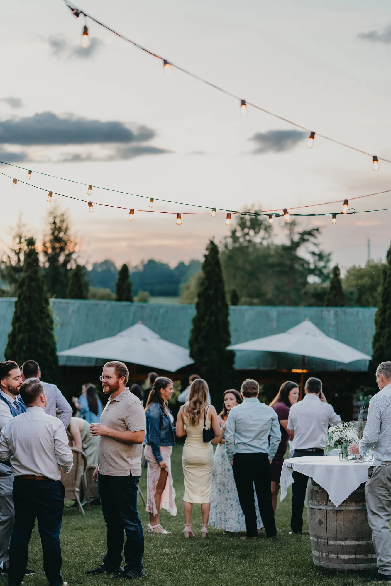 Guests mingling at cocktail hour under string lights at dusk