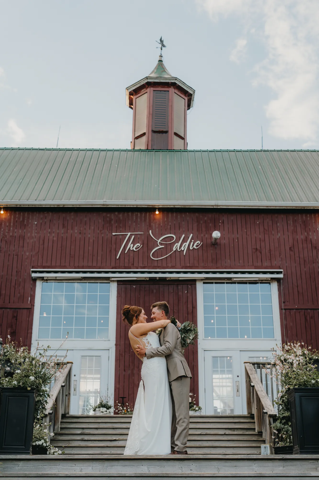 Bride and groom embracing in front of The Eddie sign at golden hour