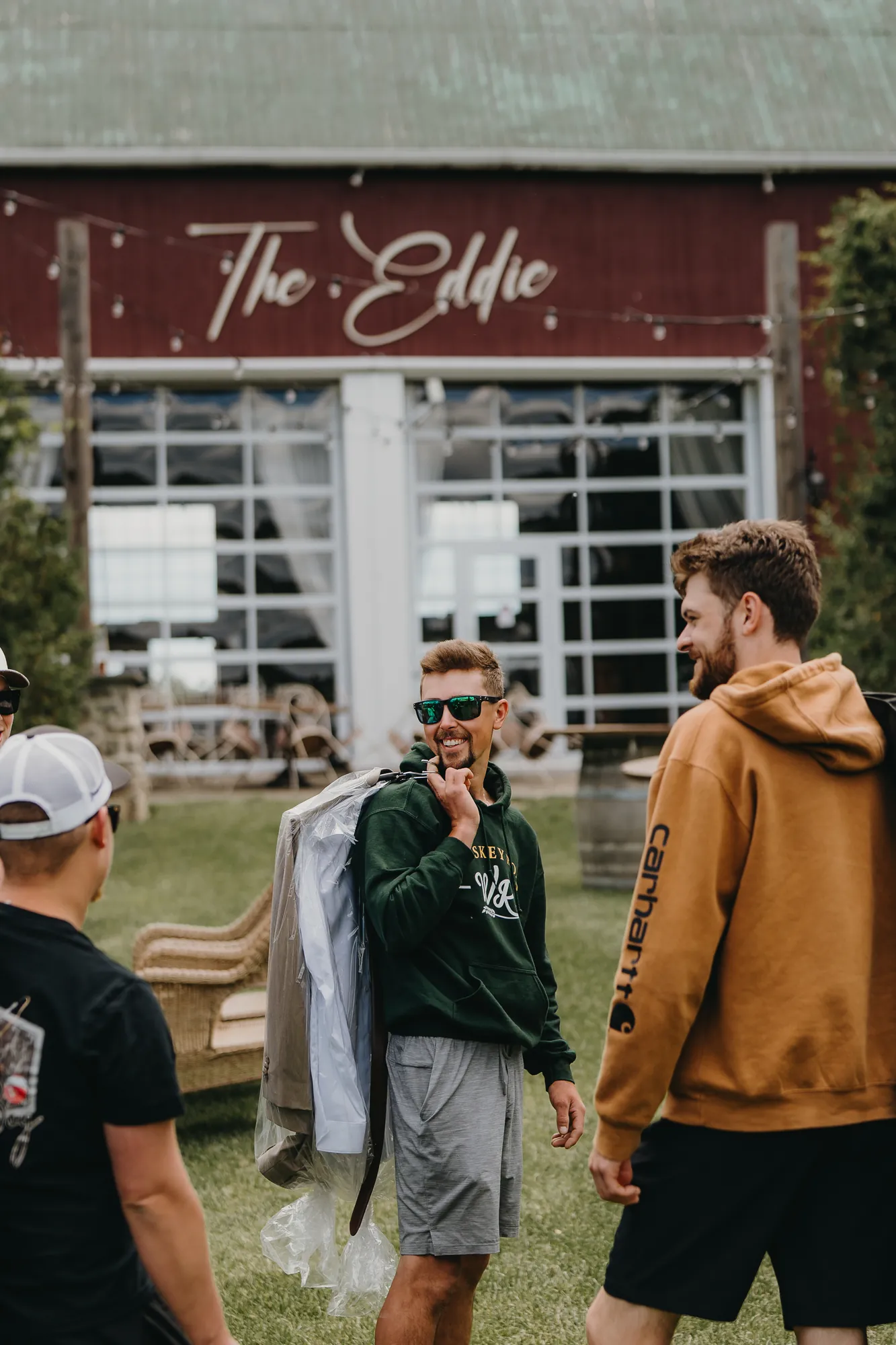 Groomsmen laughing outside the barn at The Eddie Hotel & Farm before the ceremony