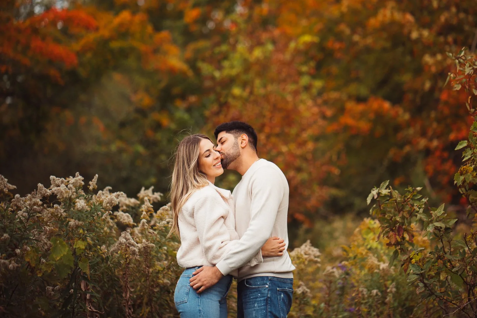 Engaged couple surrounded by red and orange fall foliage