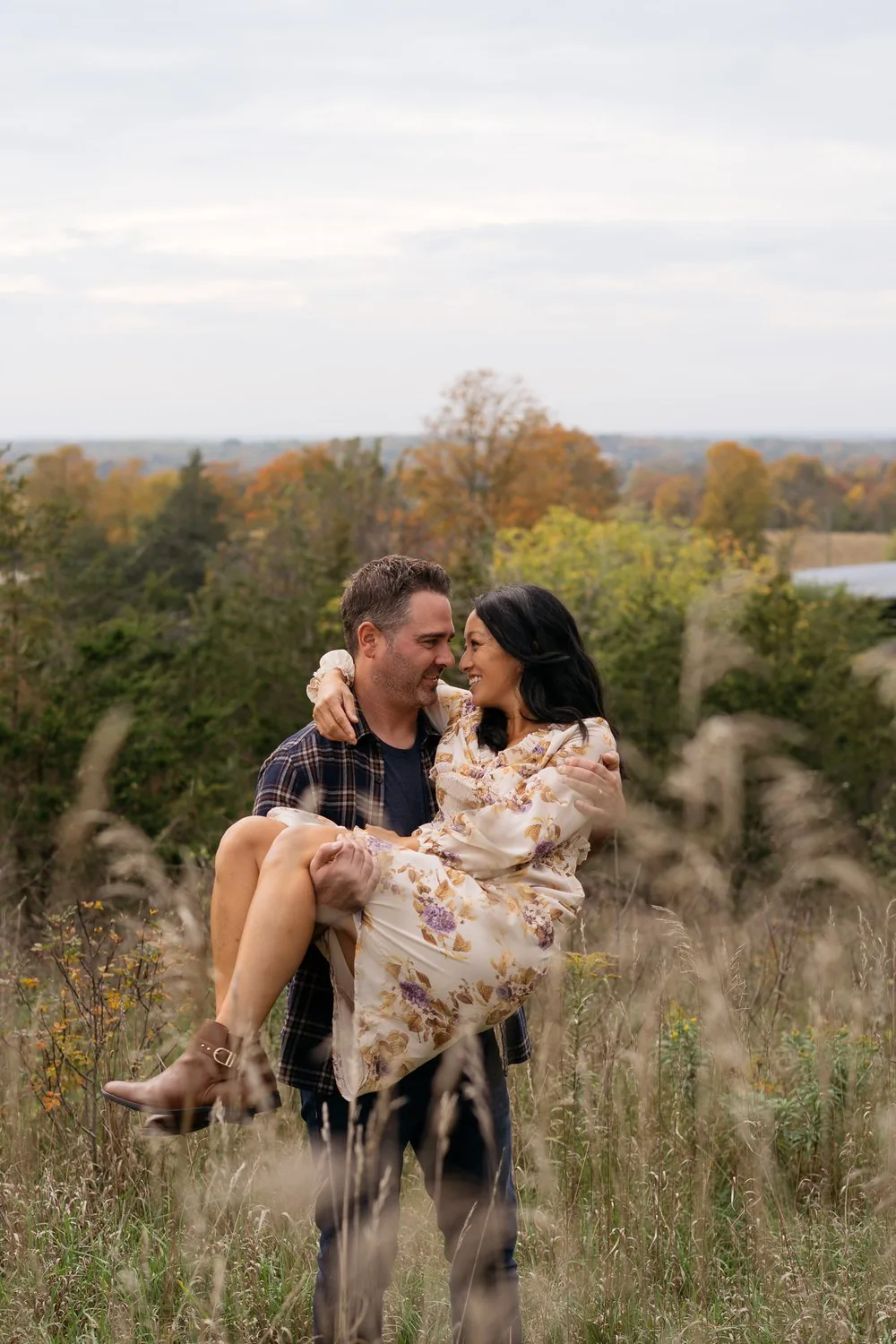 Engagement session in a Prince Edward County field, partner lifted in the tall grass