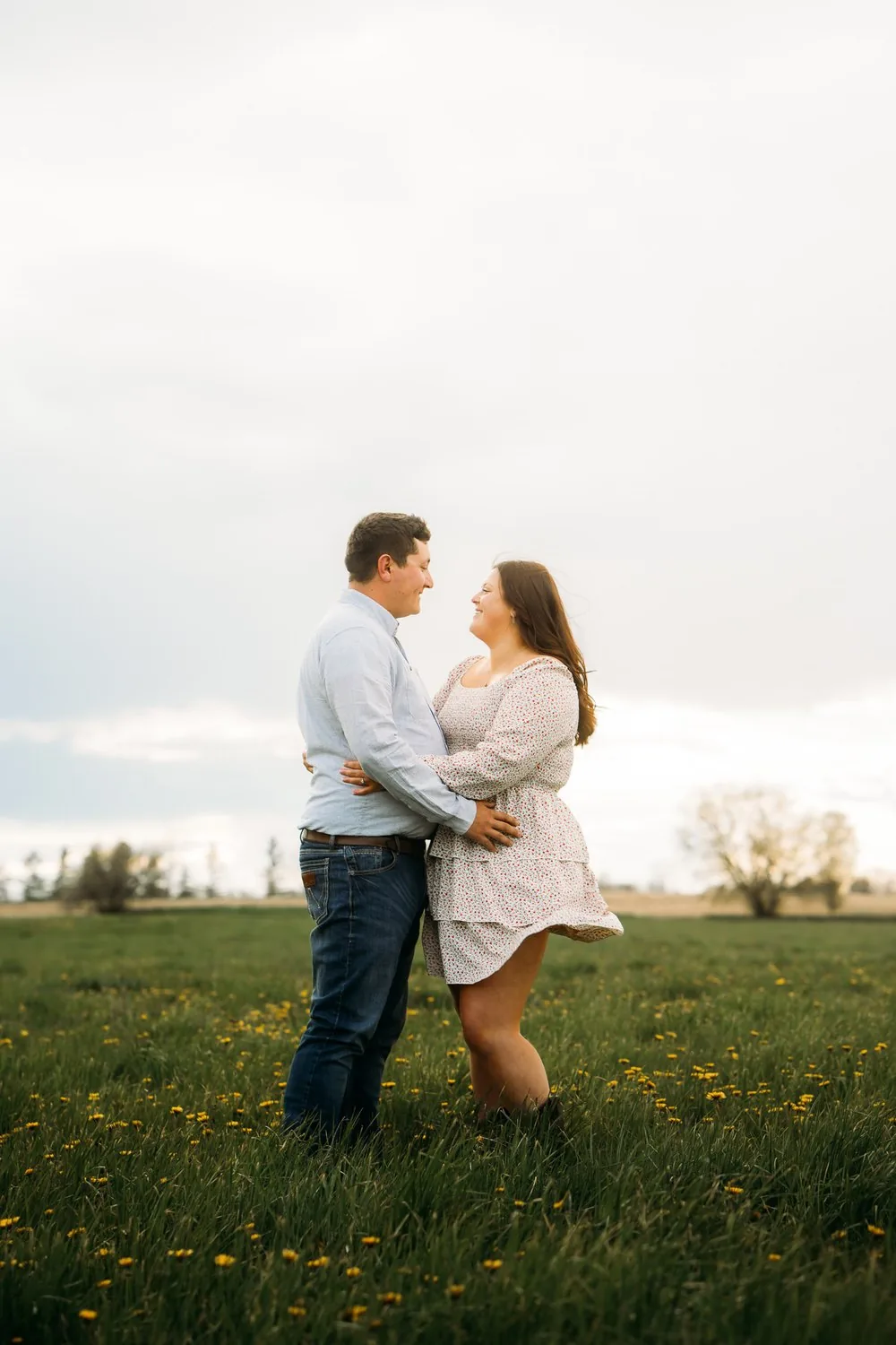 Couple embracing in a spring field of dandelions during their engagement session